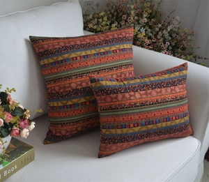 Detail of bohemian geometric throw pillow set in orange and blue on a sofa