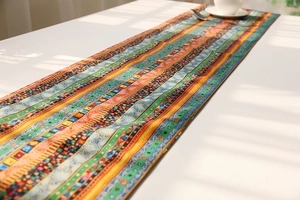 Detail of bohemian cotton linen table runner with colorful geometric patterns on white table