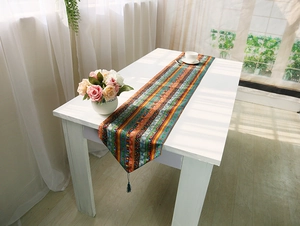 Detail of bohemian style colorful striped table runner with elegant blue fringe tassels