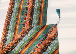Close-up of bohemian table runner with colorful geometric patterns and blue silk tassels