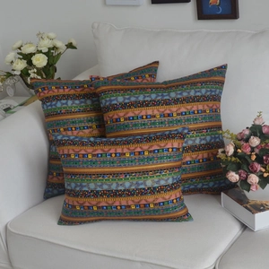 Detail of bohemian ethnic print cushion covers with colorful stripes on a white sofa