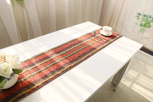 Detail of bohemian red cotton linen table runner with intricate geometric woven patterns