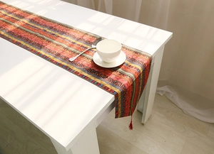 Close-up of bohemian table runner with ethnic stripes and red fringe tassels decoration