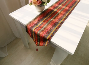 Detail of bohemian cotton linen table runner with ethnic geometric patterns and tassels