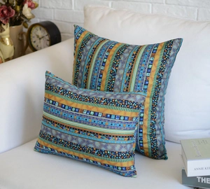 Detail of bohemian geometric throw pillows on white sofa with vintage decor and books