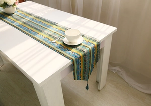 Detail of bohemian cotton linen table runner with ethnic stripes and blue tassels