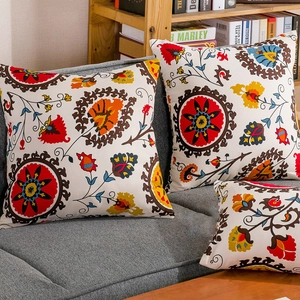 Three bohemian ethnic sunflower pattern cushions on a gray sofa in a cozy home setting