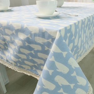 Close-up of bohemian blue linen tablecloth featuring white whale patterns and lace edges