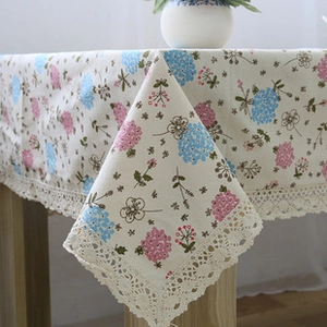 Close-up of floral linen tablecloth featuring delicate lace edges and pink hydrangea patterns