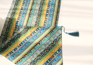 Close-up of ethnic style cotton linen table runner with blue green patterns and tassels