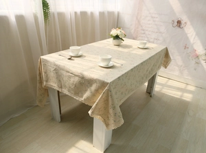 Close-up of beige floral cotton linen tablecloth with elegant white lace border detail