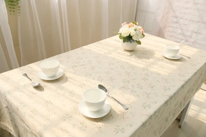 Detailed close-up of pastoral floral tablecloth with lace border on a dining table