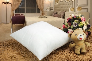 Detailed view of square white pillow insert with PP cotton filling on brown plush carpet