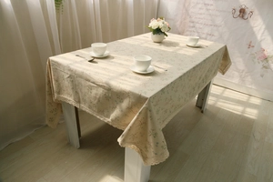 Close-up of rectangular linen tablecloth featuring floral patterns and crochet lace edges
