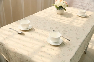 Close-up of floral cotton linen tablecloth with delicate lace edges and pink roses