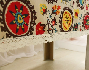 Close-up of Bohemian linen tablecloth featuring colorful floral patterns and lace edges