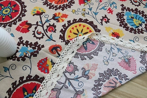 Detail of bohemian cotton linen tablecloth with ethnic floral print and lace edge