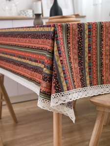 Close-up of bohemian linen tablecloth featuring colorful ethnic patterns and white lace trim