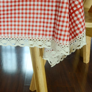 Red and white checkered tablecloth with decorative lace edges on a wooden table