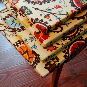 Detail of stacked bohemian linen chair cushions with colorful ethnic floral patterns