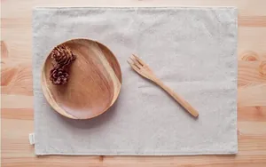 Close-up of beige linen placemat texture with fine stitching on a light wood background