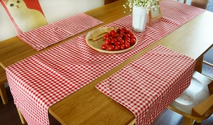 Detail of red and white plaid cotton linen table runner and placemats on wooden table