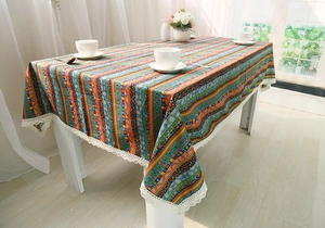 Detail of bohemian striped tablecloth with decorative white wide lace edging on a table