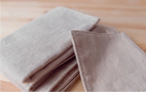 Macro view of stacked linen table placemats showing natural fiber texture and neat stitching