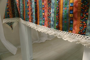 Close-up of colorful striped cotton linen tablecloth with delicate white lace trim details