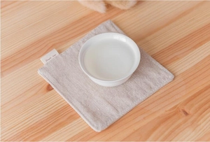 Detail of square beige linen placemat with Simple home label on a wooden table