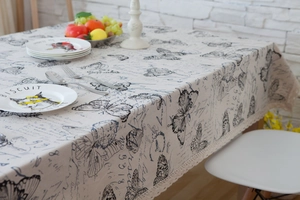 Macro shot of rustic cream cotton linen tablecloth with butterfly prints and lace edge