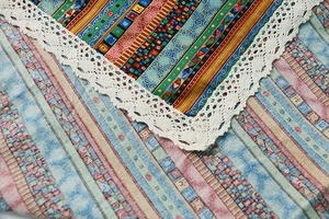 Macro shot of ethnic bohemian tablecloth with colorful patterns and white lace edges
