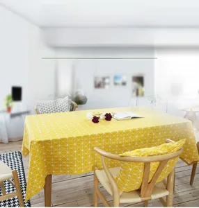 Detailed close-up of yellow cotton linen tablecloth and matching cushion with white patterns