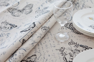 Detail of linen tablecloth with vintage butterfly prints and elegant script patterns