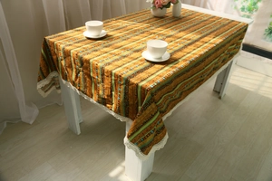Detail of bohemian cotton linen tablecloth with orange stripes and white lace trim