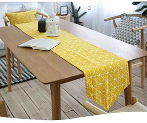 Macro detail of yellow table runner with white geometric triangle patterns on wood table