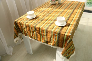 Detail of bohemian striped linen tablecloth featuring vibrant patterns and white lace edges