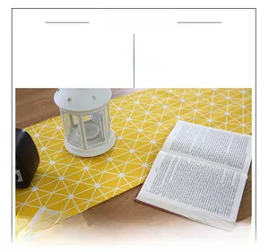 Detail of yellow geometric table runner on wooden desk with lantern and book décor