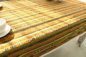 Detail of bohemian cotton linen tablecloth with orange geometric stripes and white lace edges
