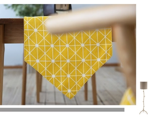 Detail of yellow geometric table runner with grid pattern on a wooden dining table