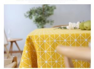 Detail of yellow cotton linen tablecloth with white geometric triangle pattern and drape