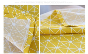 Detailed view of yellow linen tablecloth featuring white star patterns and fine hem stitching
