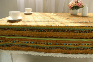 Detail of bohemian ethnic linen tablecloth with geometric patterns and white lace trim