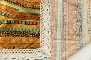 Detail of bohemian cotton linen tablecloth with ethnic patterns and white lace edges