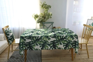 Vue détaillée d'une nappe imperméable avec feuilles de Monstera et housse de coussin assortie