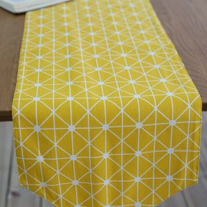 Modern yellow table runner with geometric white triangle pattern on dark wood