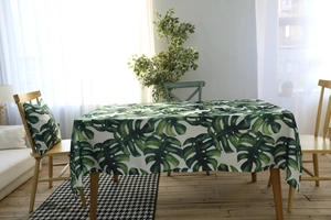 Détail de la nappe en coton à motif feuilles de monstera vertes avec coussin assorti