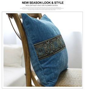 Detail eines blauen Samtkissens mit aufwendiger Boho-Stickerei auf einem Holzstuhl