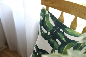 Detail of tropical monstera leaf pillow cover with hidden zipper on wooden chair