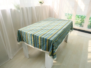 Close-up of bohemian linen tablecloth with colorful stripes and white lace edges